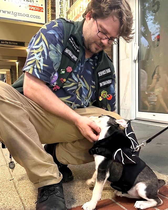 Tre Plaisted crouching with a puppy